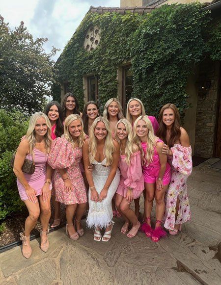 A group of women in pink dresses are posing for a picture.