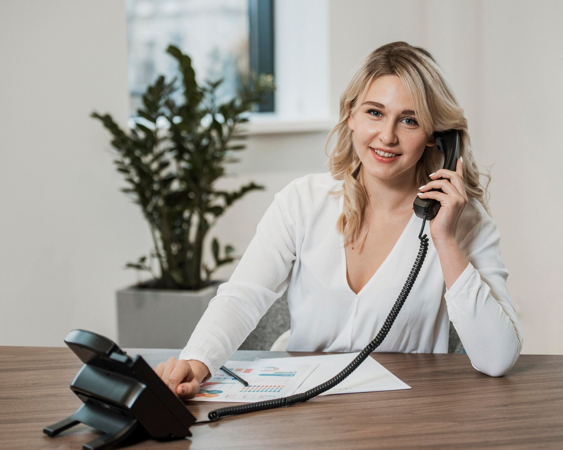 A woman is sitting at a desk talking on a phone.