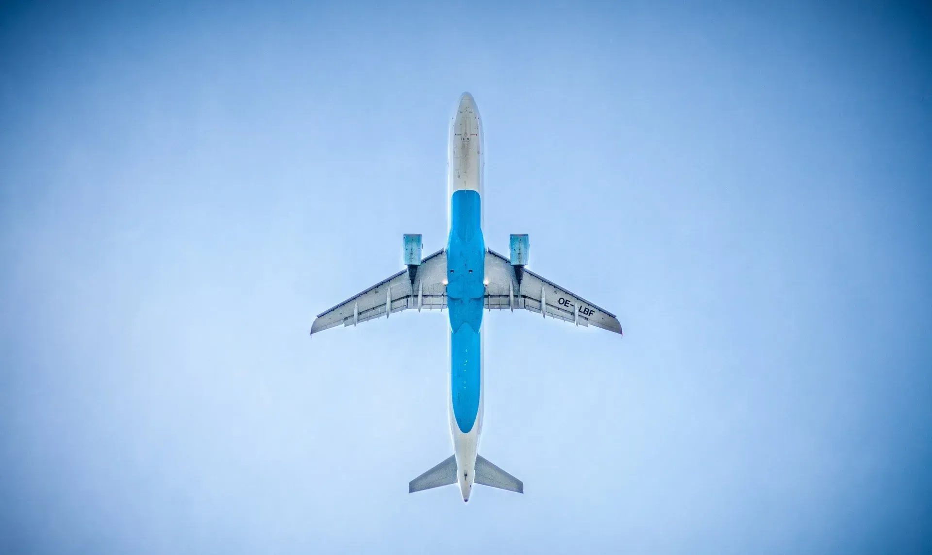 A blue and white airplane is flying through a clear blue sky.