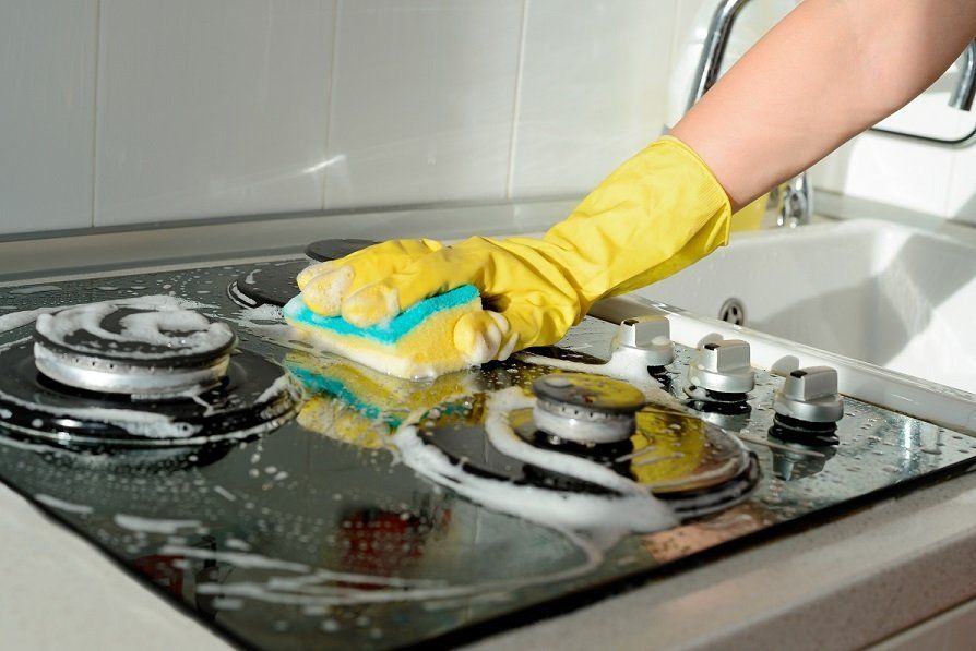 Professional house cleaner in Mackay is cleaning the kitchen of a residential home.