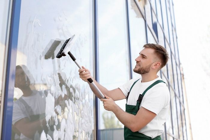Professional window cleaner scrubbing the exterior windows of a corporate building in Mackay, QLD.