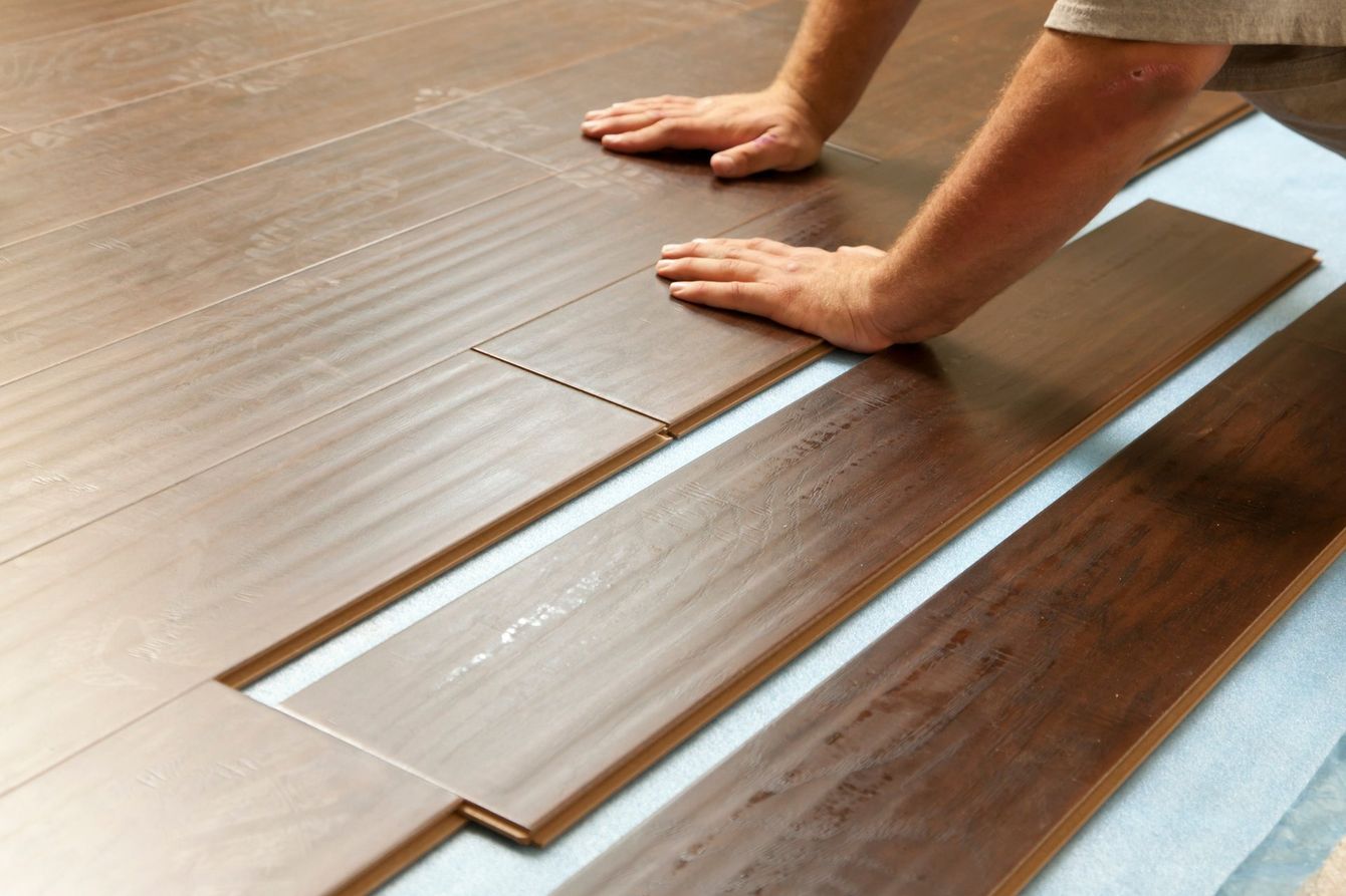 A person is installing a wooden floor in a room.