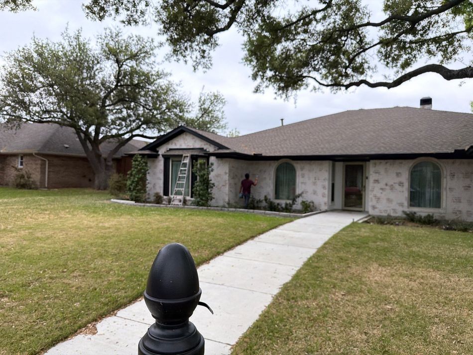 Single-story brick house with a large front lawn under an overcast sky
