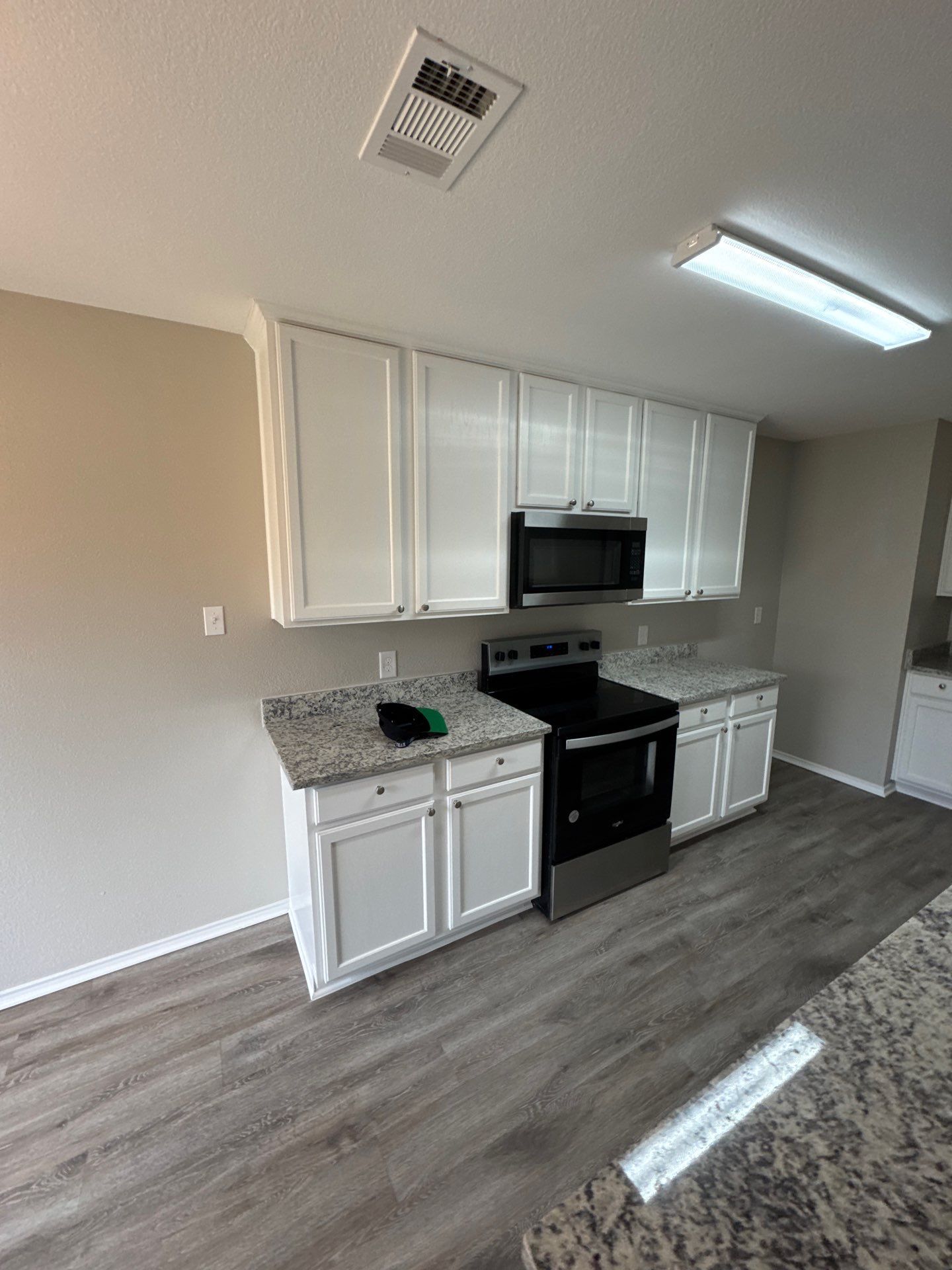 Two electricians working on an electrical panel outside a building. One holds a cable.
