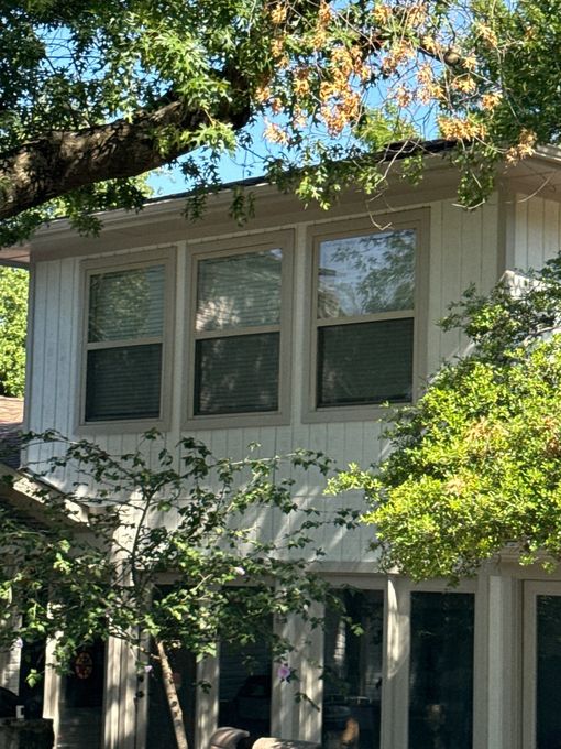 Front porch with brick steps, double glass doors, pumpkins, and two metal chairs on a white house
