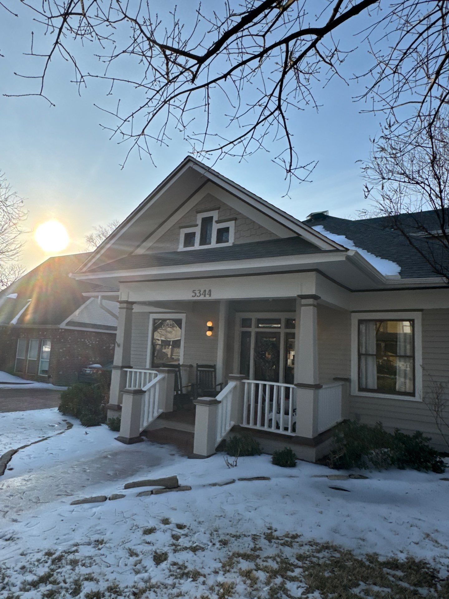 Two electricians working on an electrical panel outside a building. One holds a cable.