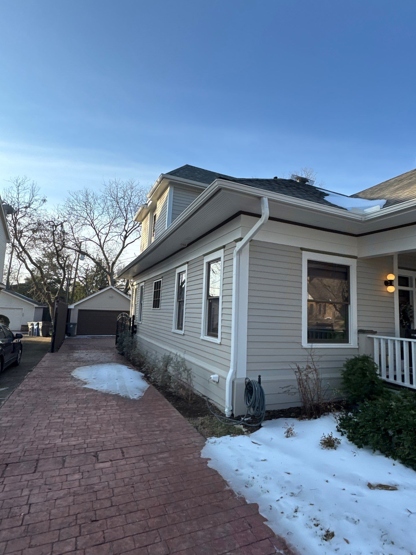 Trench dug in a grassy yard, leading to a house with black siding, and an electrical box.