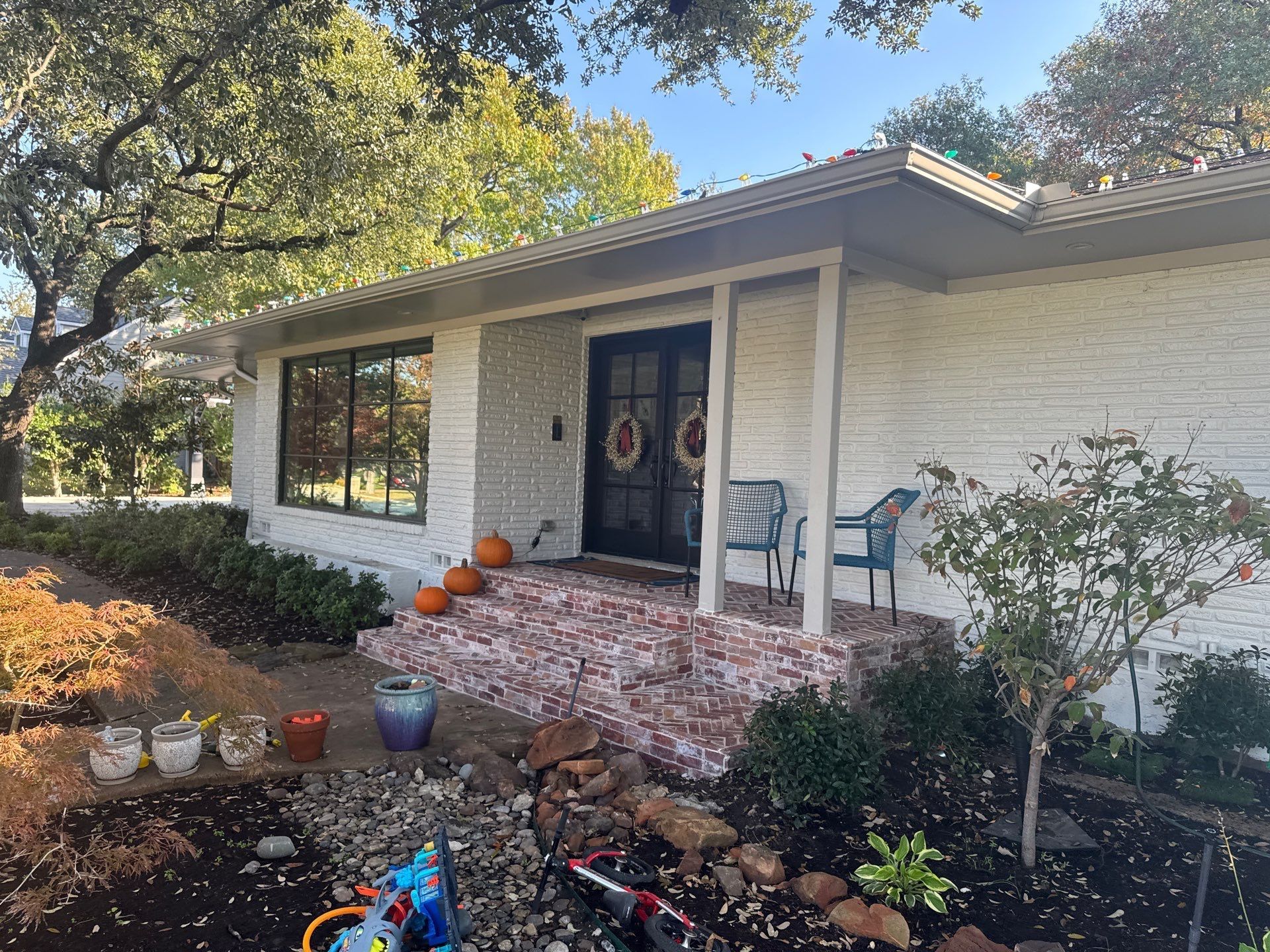 Trench dug in a grassy yard, leading to a house with black siding, and an electrical box.