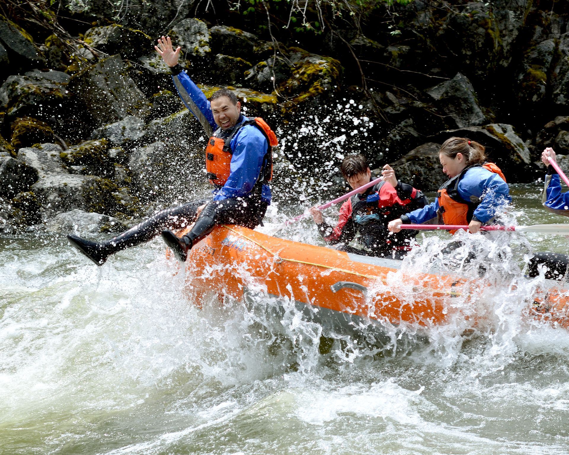 Orange raft with whitewater bull rider sitting on front of raft.