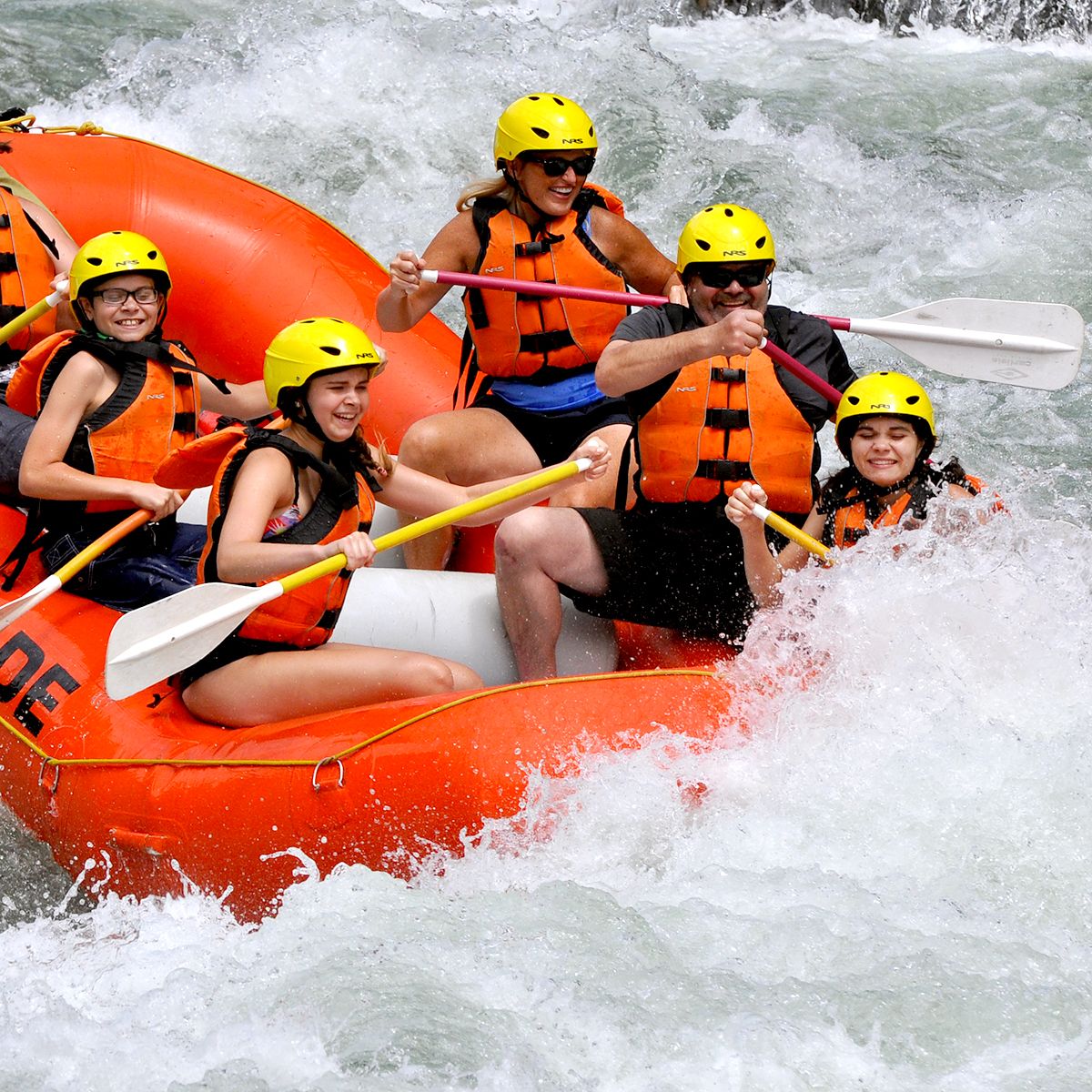 White water rafting with orange raft and people smiling.