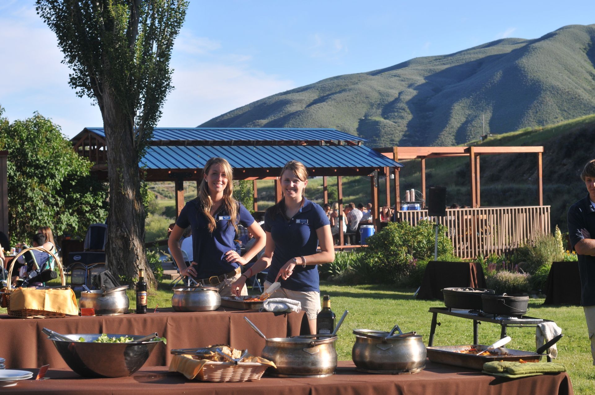 Riverside BBQ on green grass with mountains in background