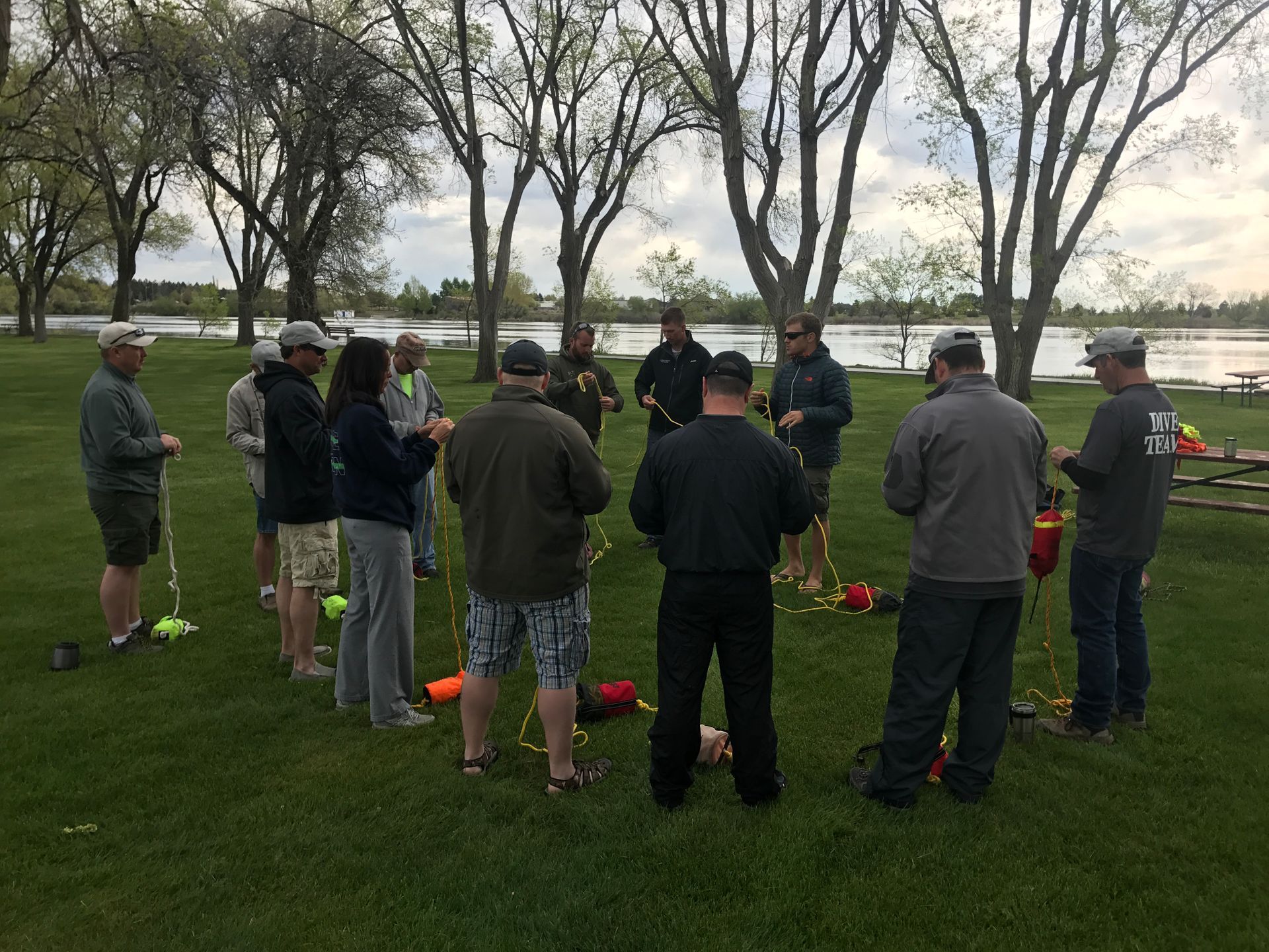 Group in grass with river in background learning about swiftwater rescue