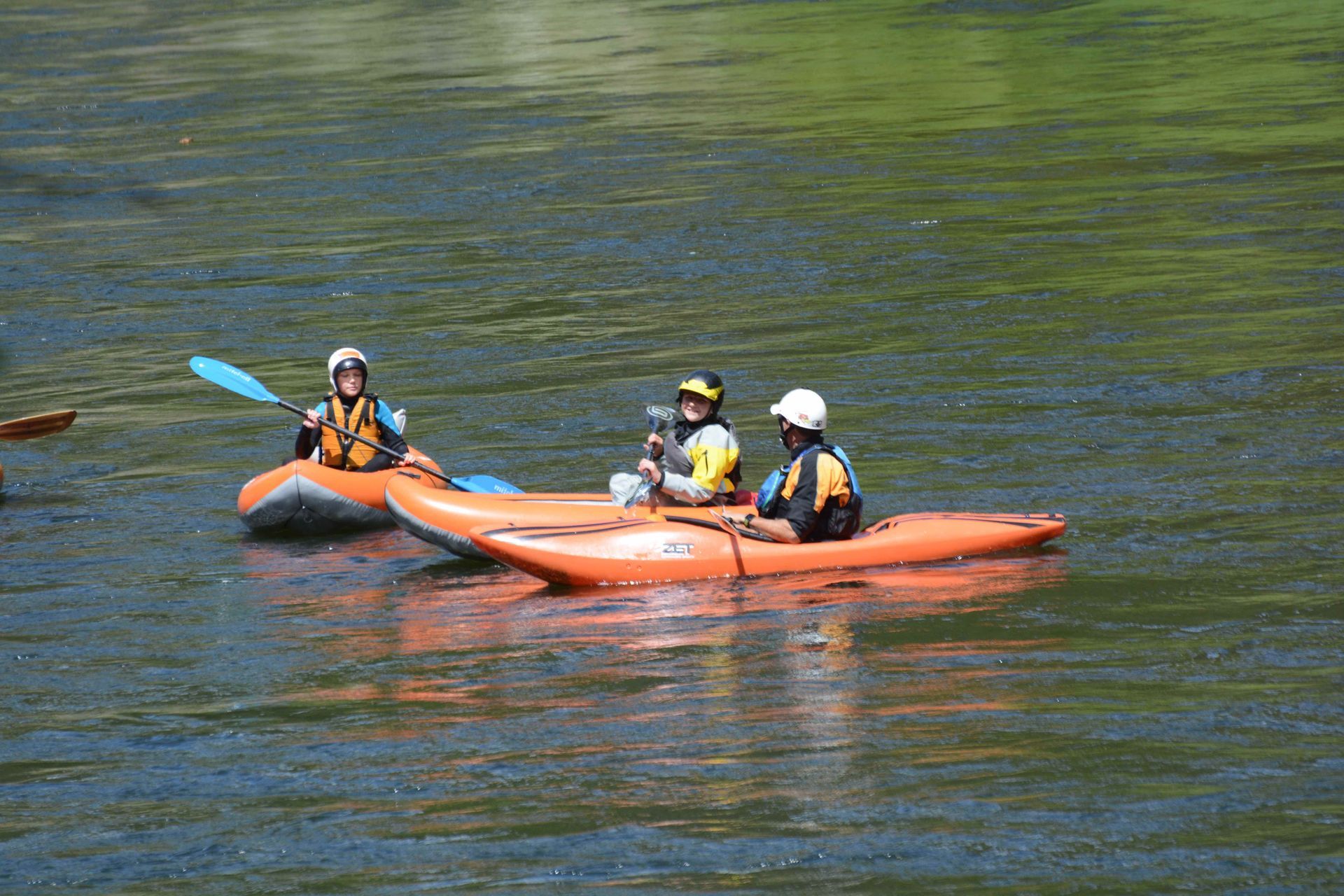 Kayaker and two inflatable kayaks in river paddling