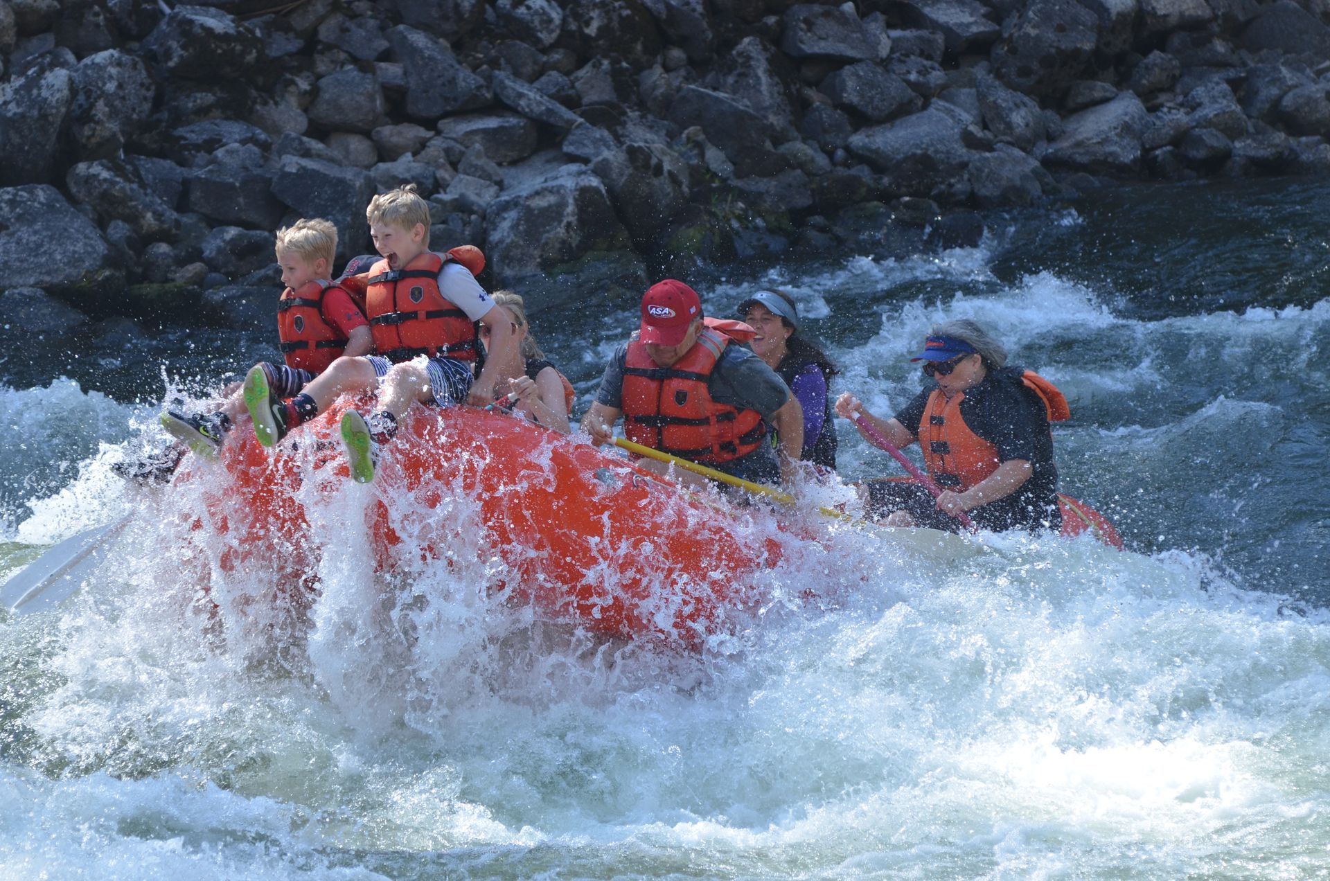 Two boys sitting in front of the raft in whitewater