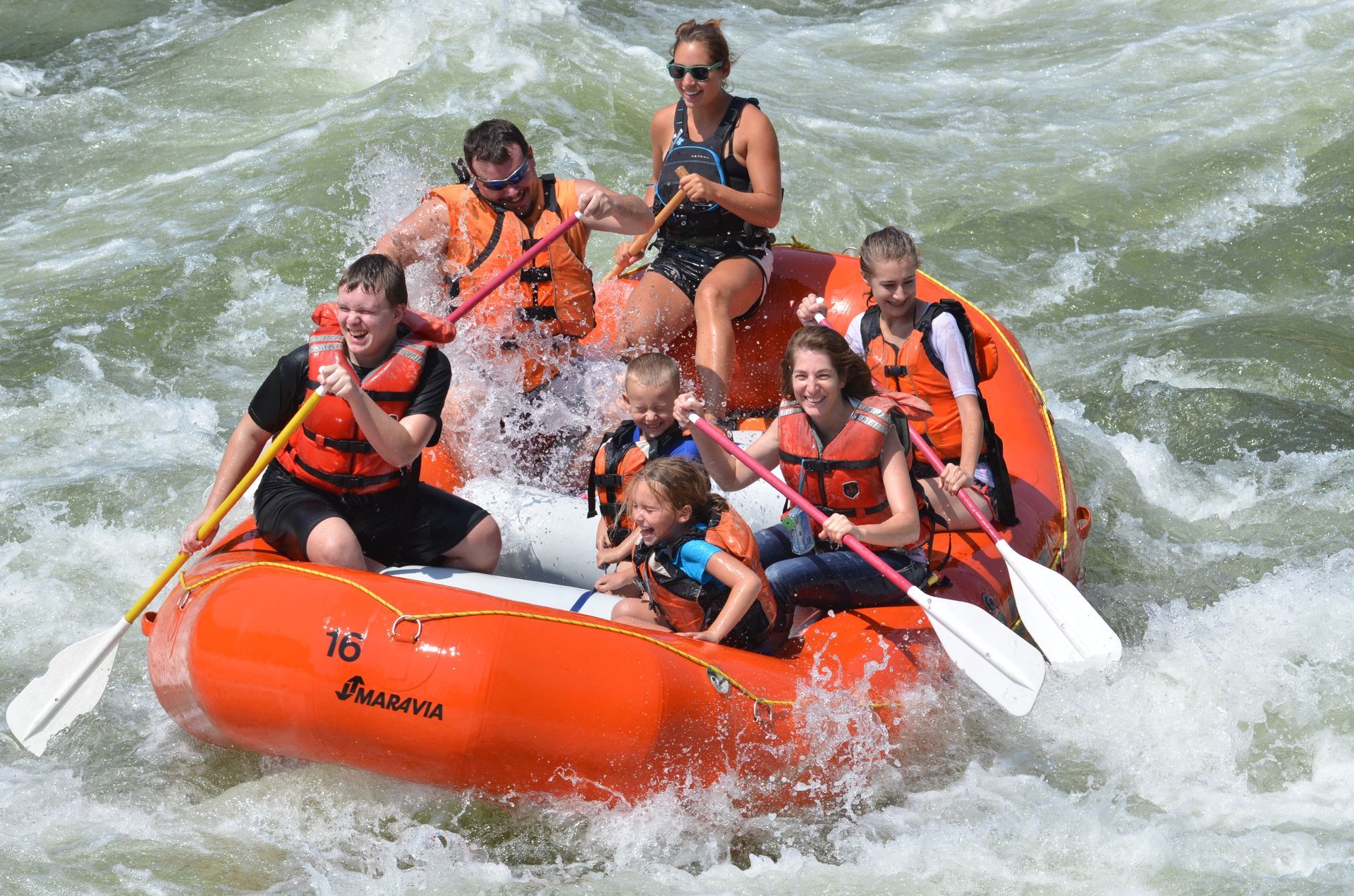 Raft guide taking family down river rafting trip