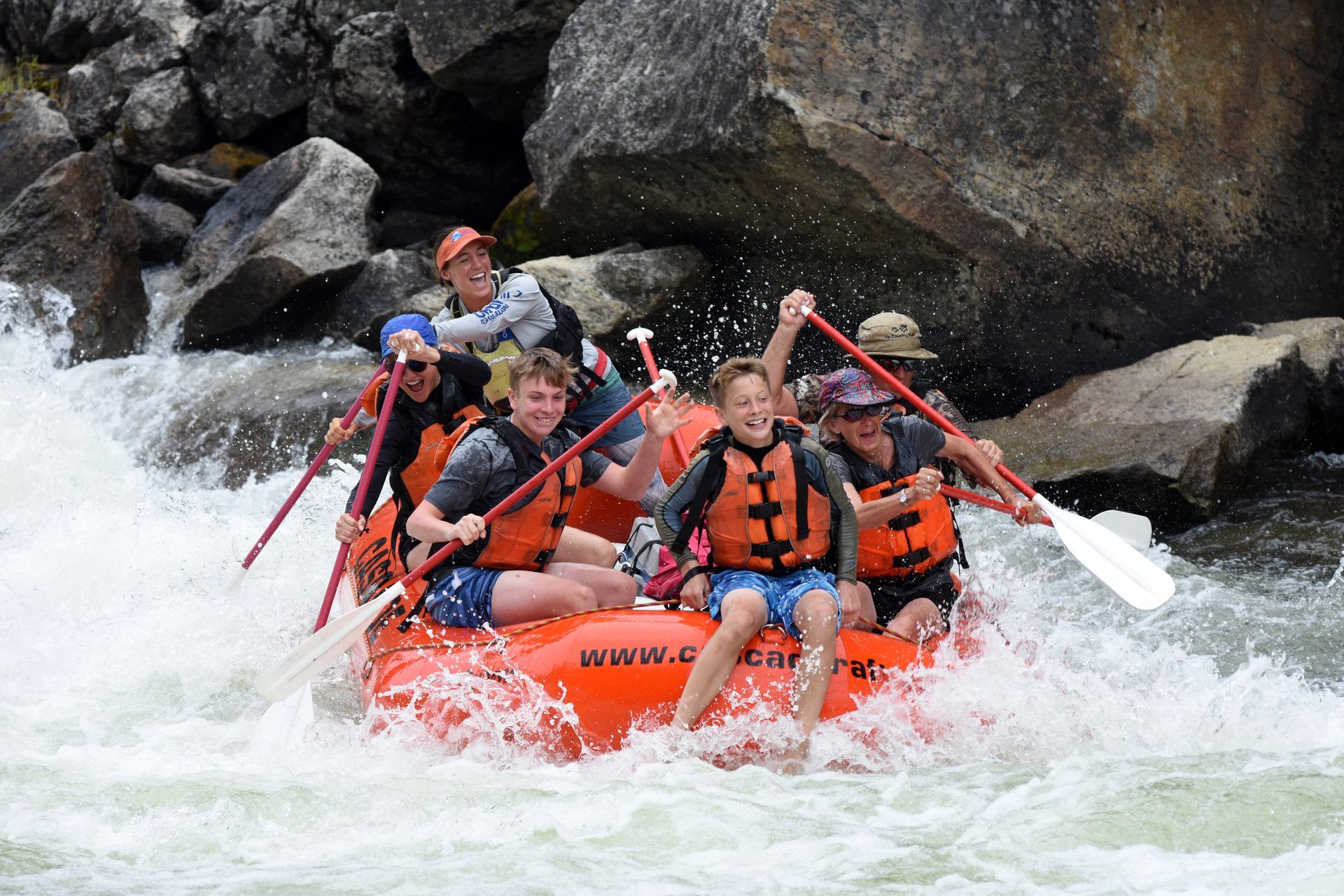 Group paddling through rapid on whitewater raft