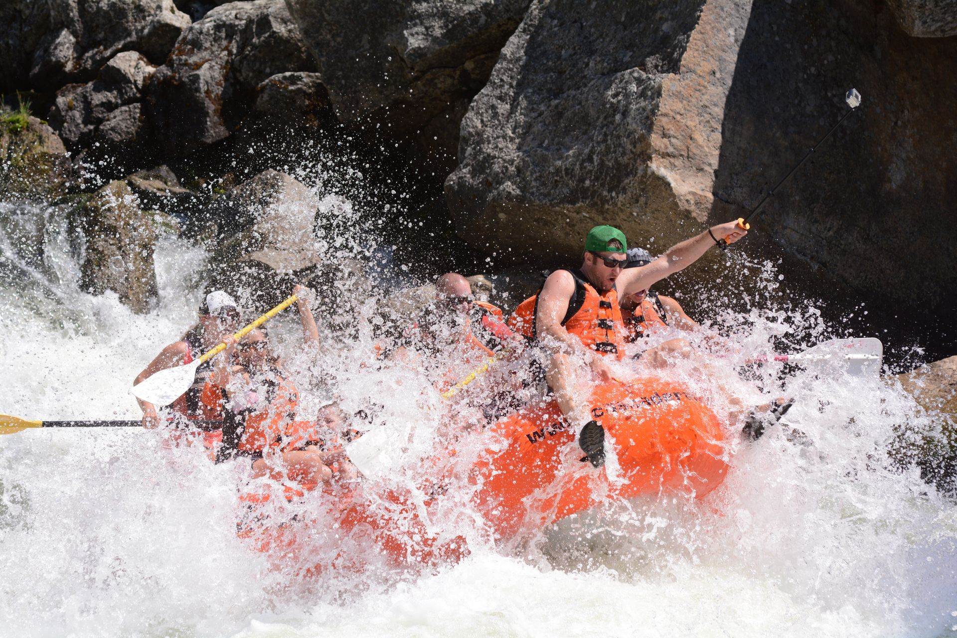 Big whitewater rapid with one person in the front and everyone else underwater