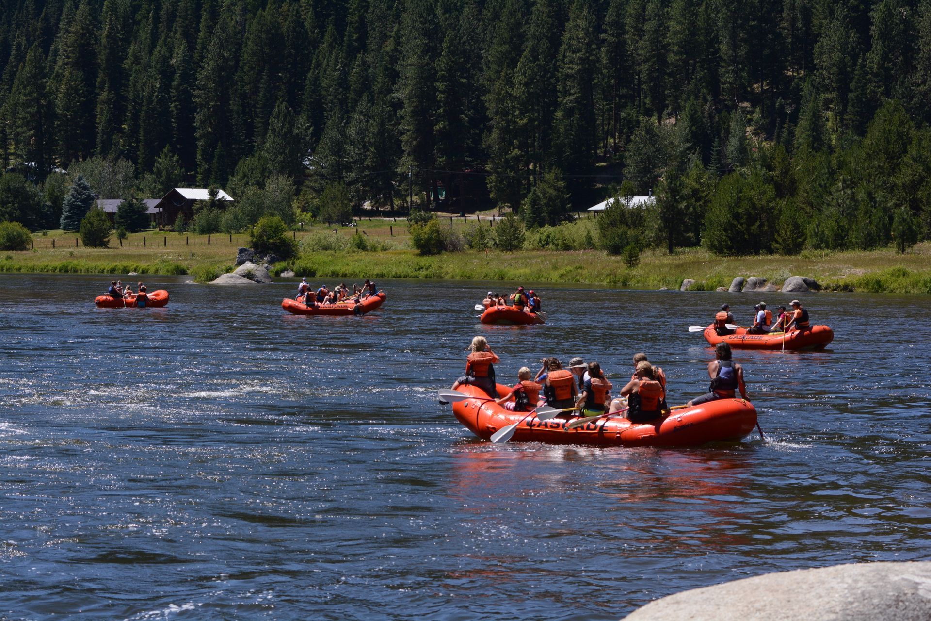 Rafting group on calm river with forest in the background