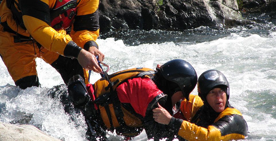 three people performing swiftwater rescue in river