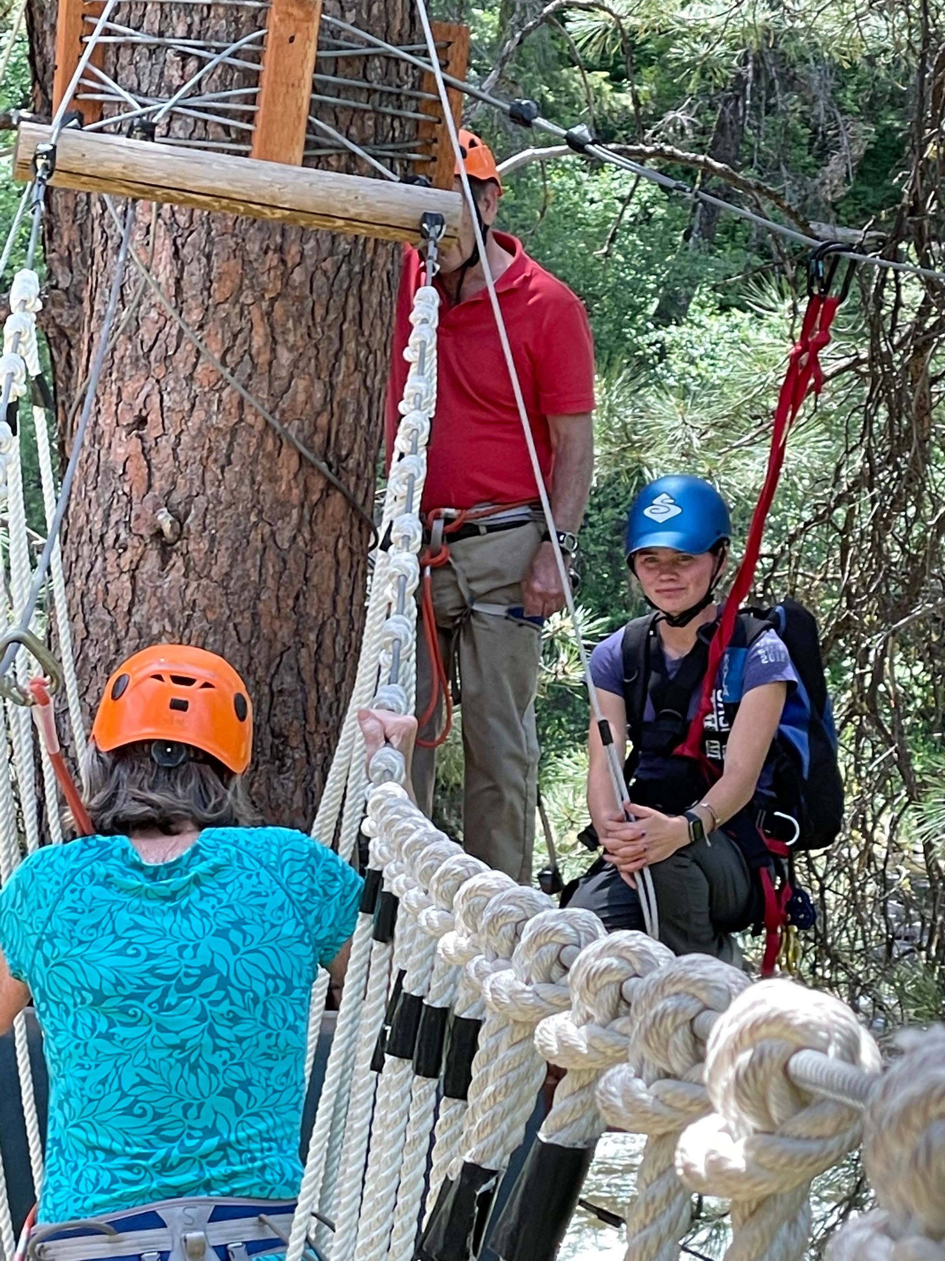 3 people going over high ropes challenge course