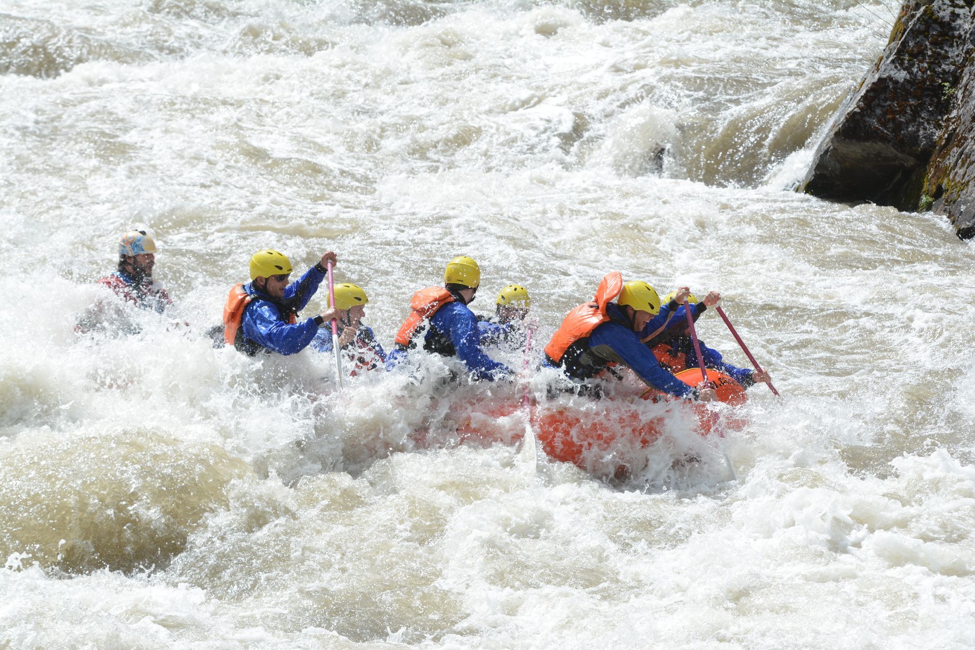 Rafters in big whitewater rapid paddling hard