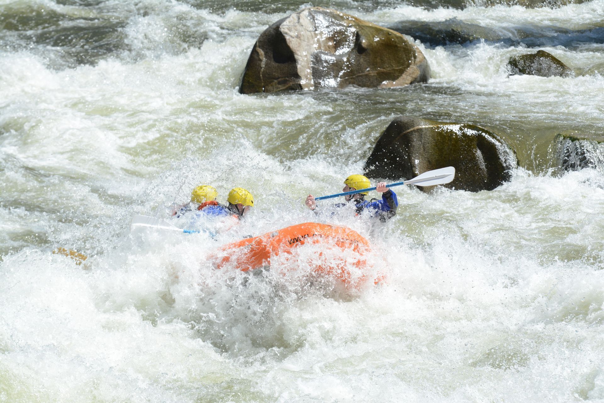 Raft almost completely underwater in whitewater rapid