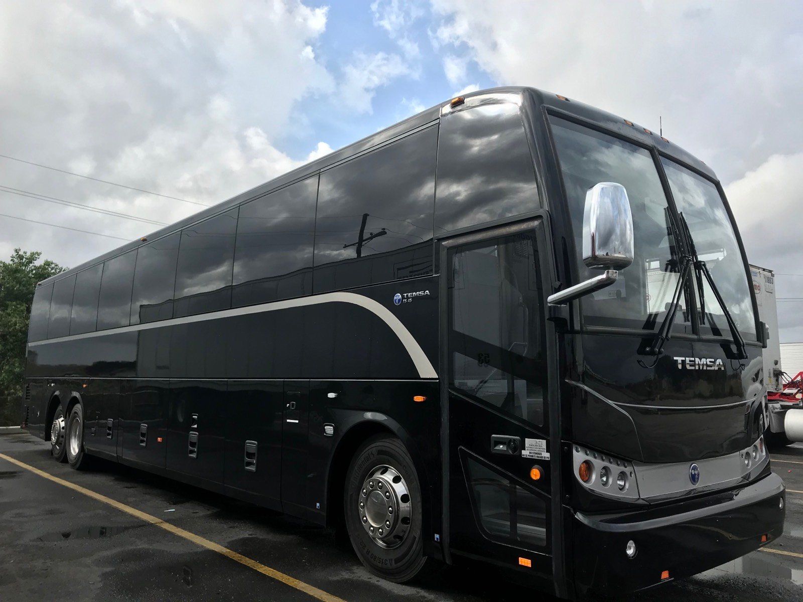 A black double decker bus is parked in a parking lot.