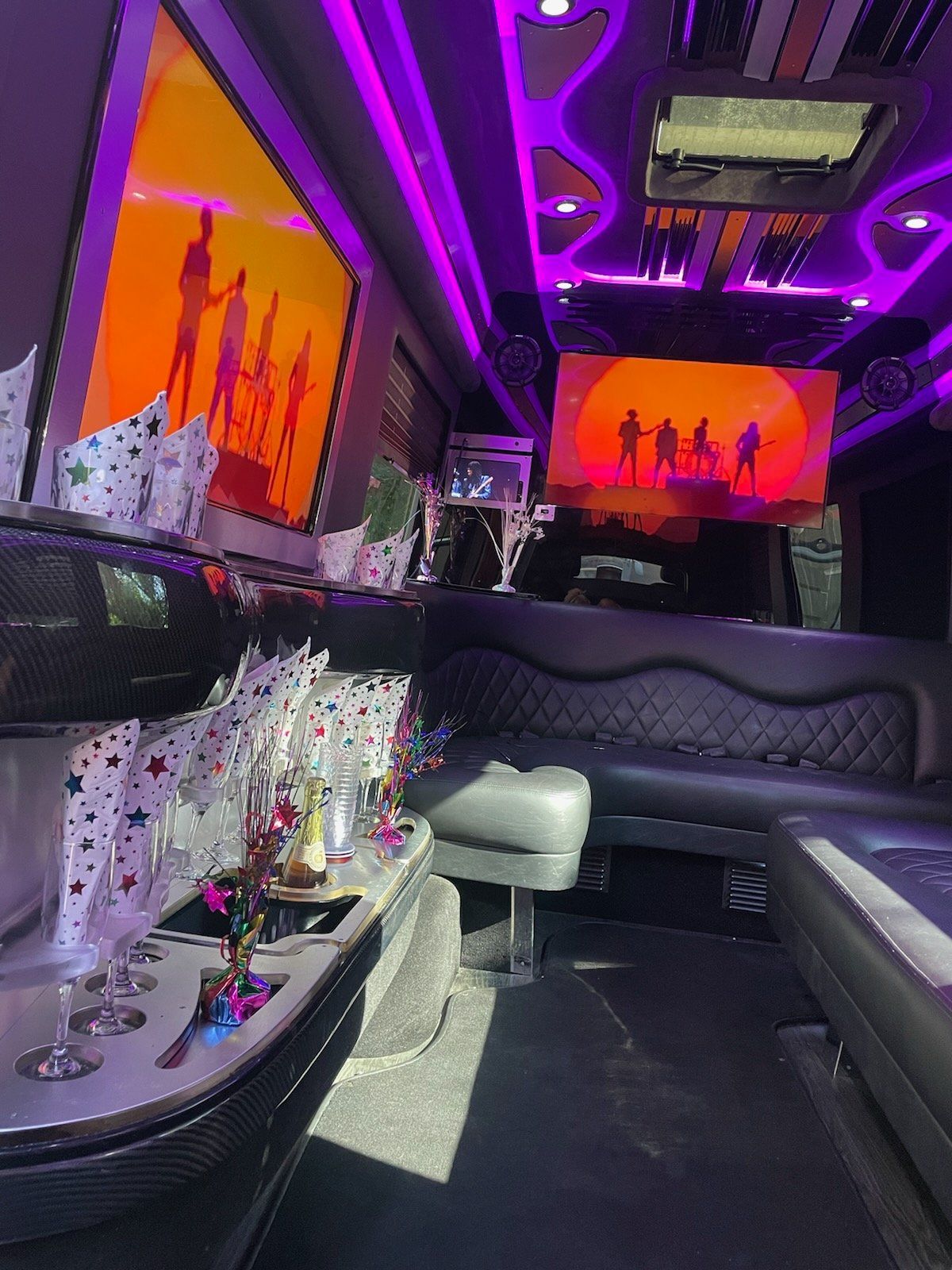 The inside of a limousine with a couch and two televisions on the ceiling.