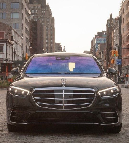 A black mercedes is parked on a cobblestone street
