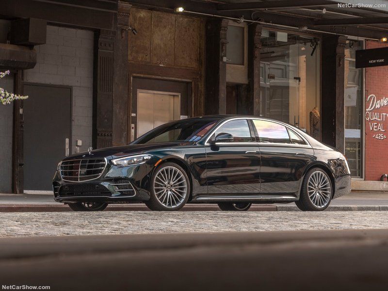 A black mercedes benz s class is parked in front of a building.