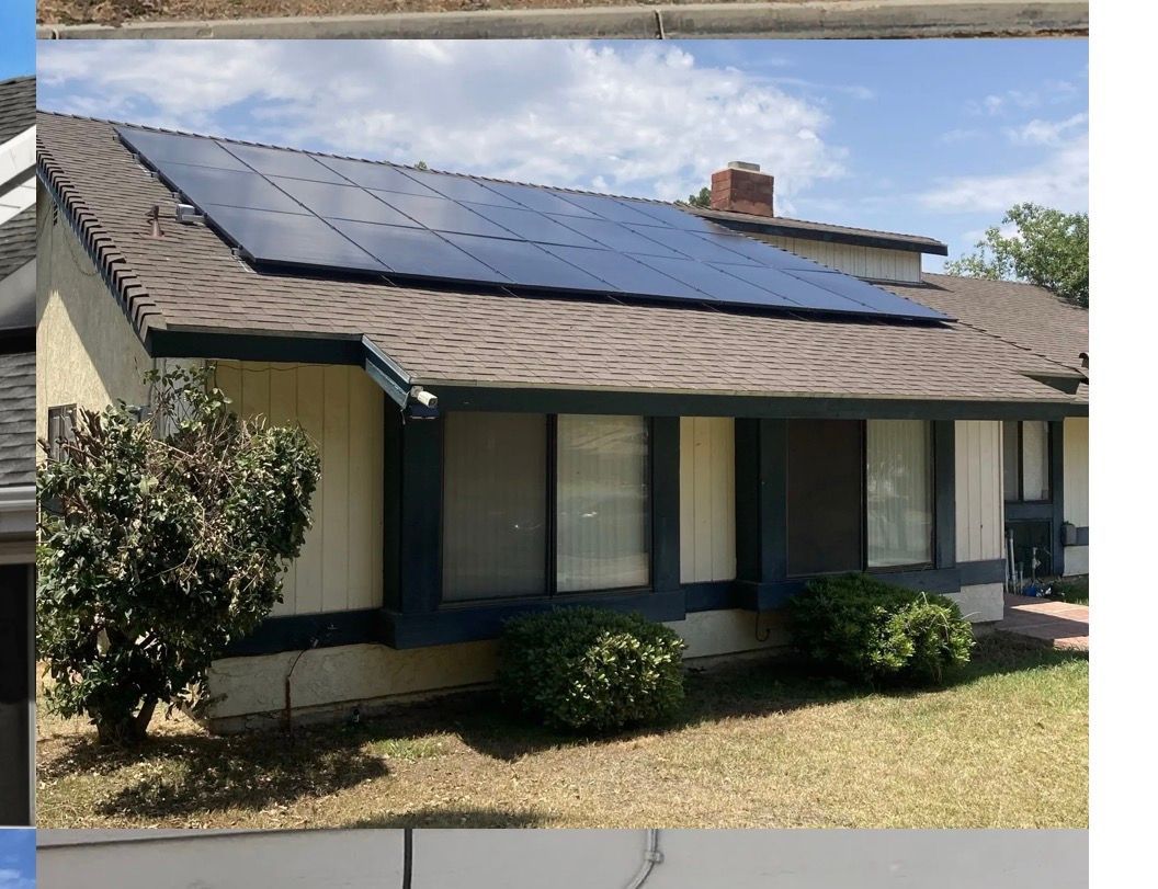 Two workers installing solar panels on a rooftop, mountains and trees in the background.