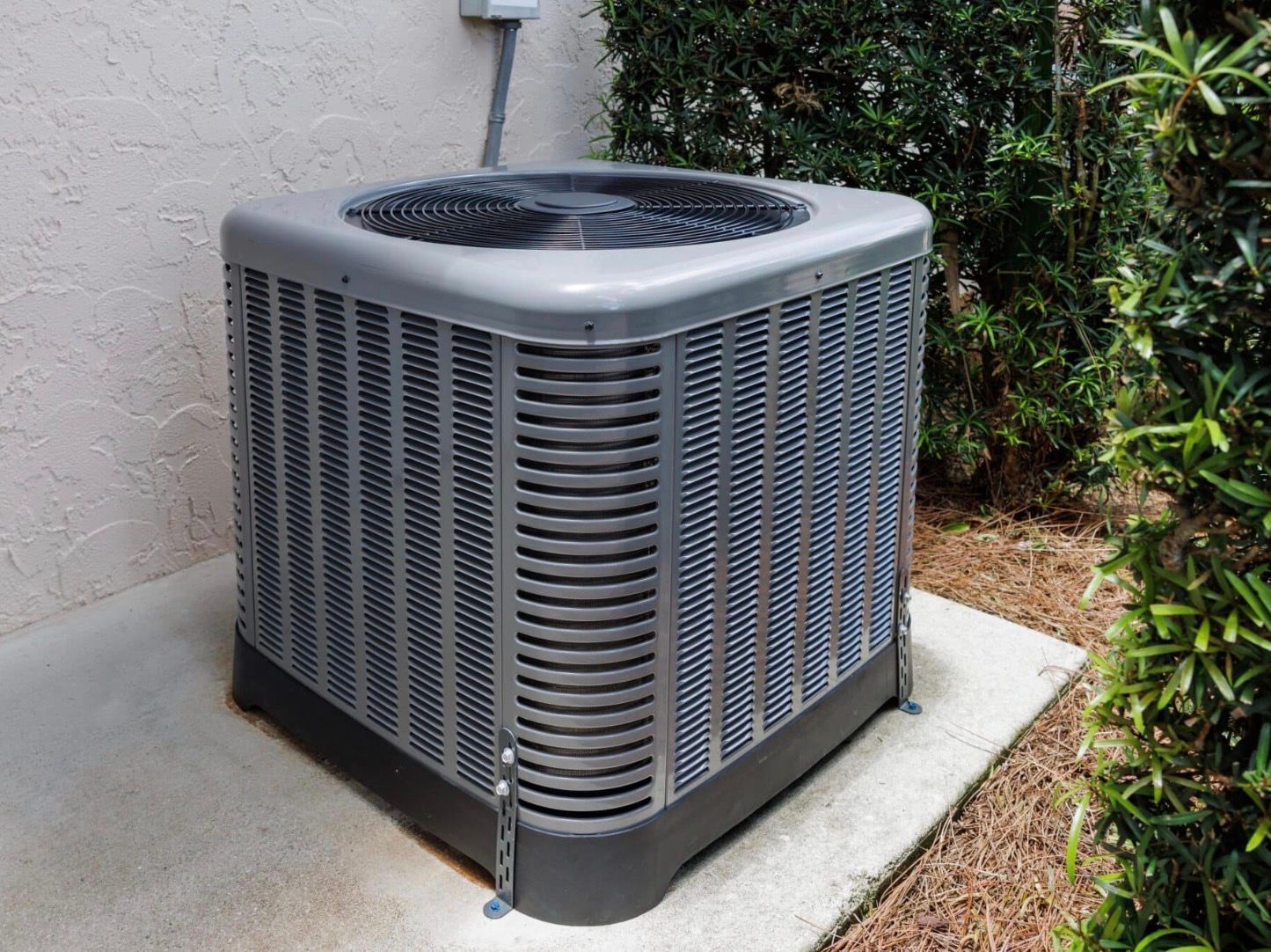 Black gate, walkway, and building with electrical boxes and a wall lantern in sunlight.
