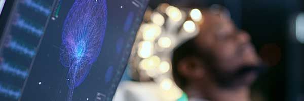 A man is holding a tablet in front of a computer screen.