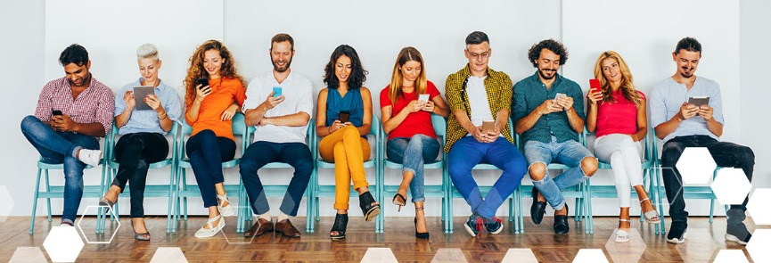A group of people are sitting in a row looking at their phones.