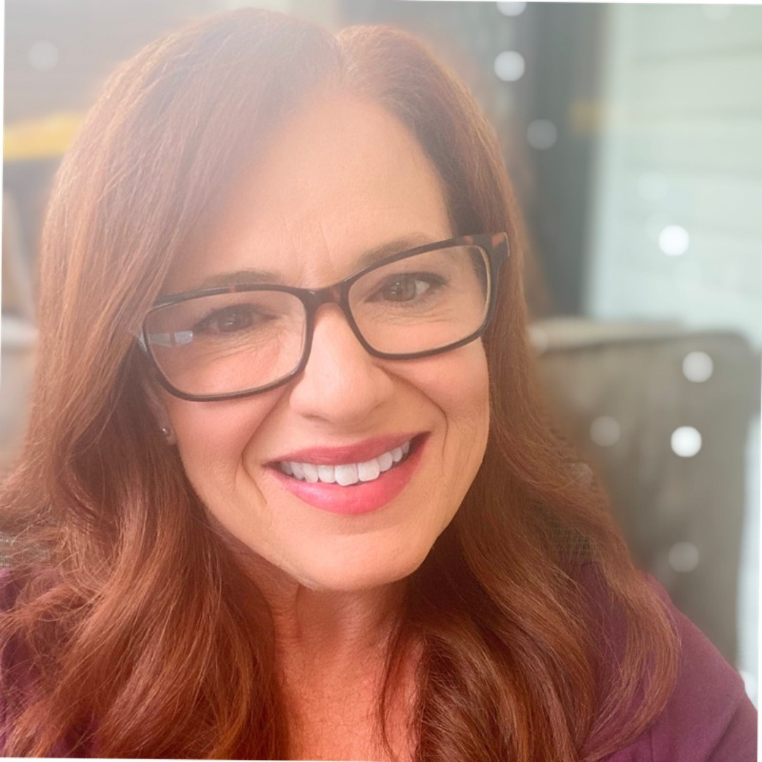 A woman wearing glasses is smiling for the camera.