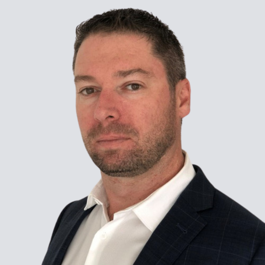 A man with a beard is wearing a suit and white shirt.