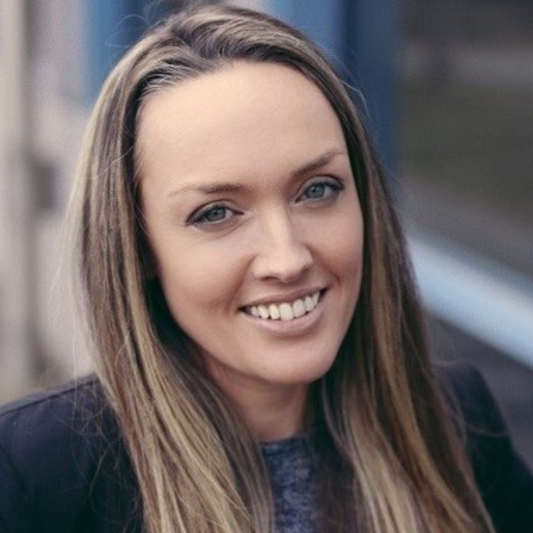 A woman with long hair is smiling for the camera.