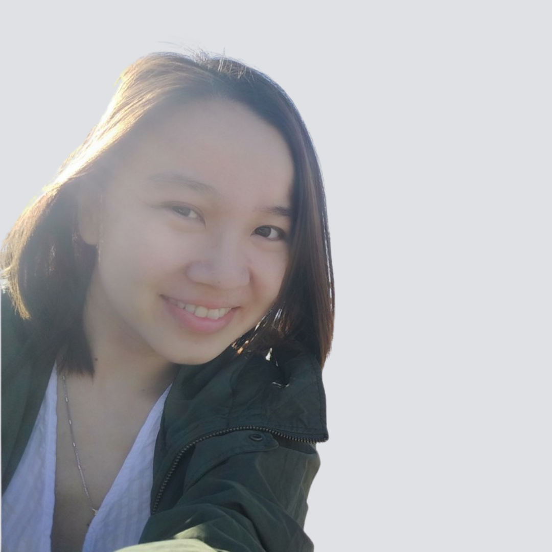 A woman wearing a green jacket and a white shirt smiles for the camera