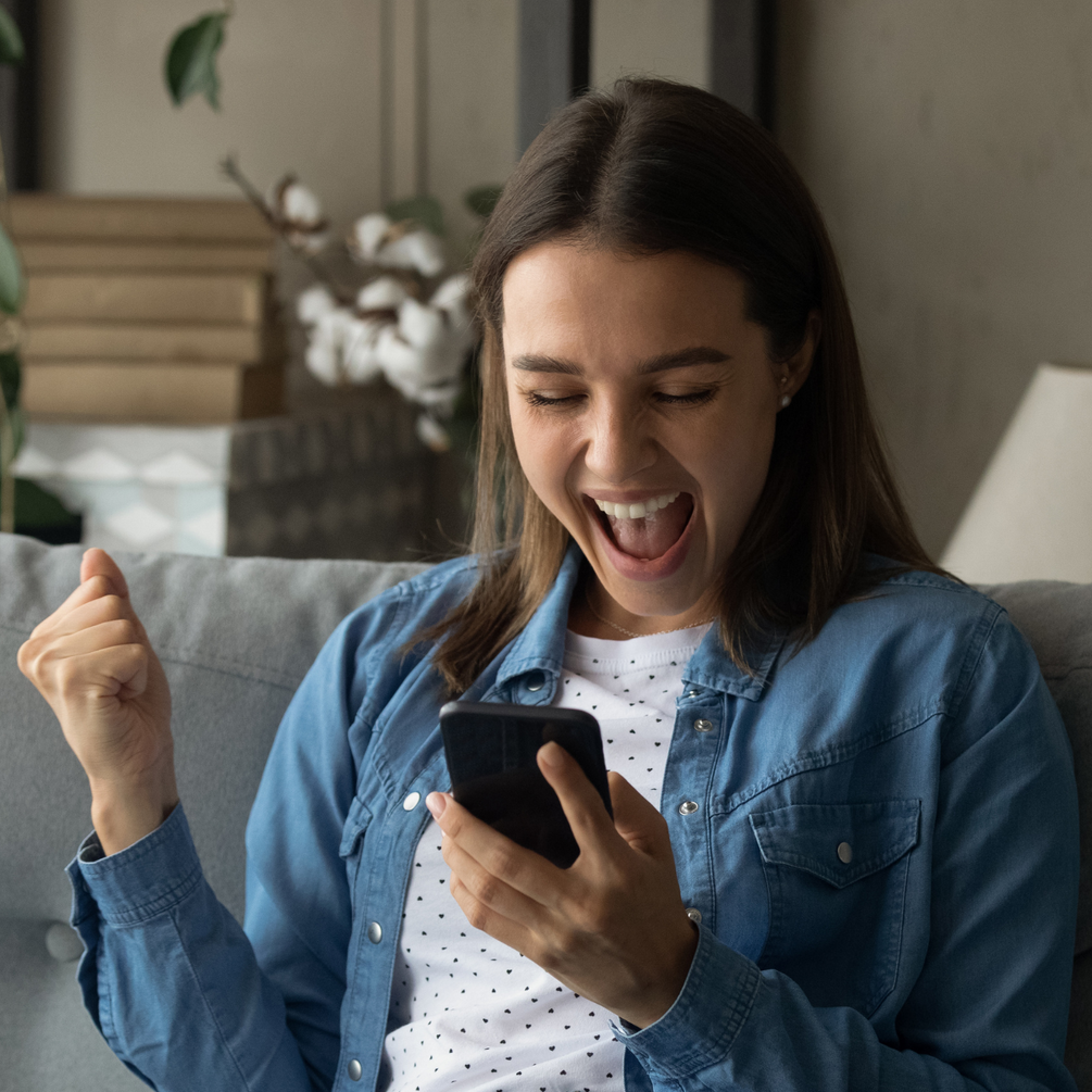 A woman grins while checking her phone