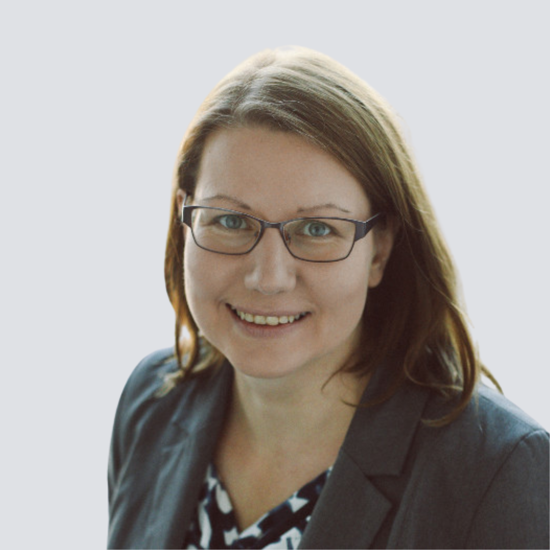 A woman wearing glasses and a suit smiles for the camera
