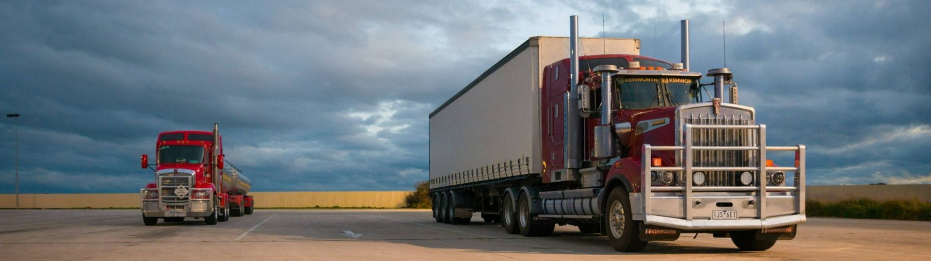 Two semi trucks are parked next to each other in a parking lot.