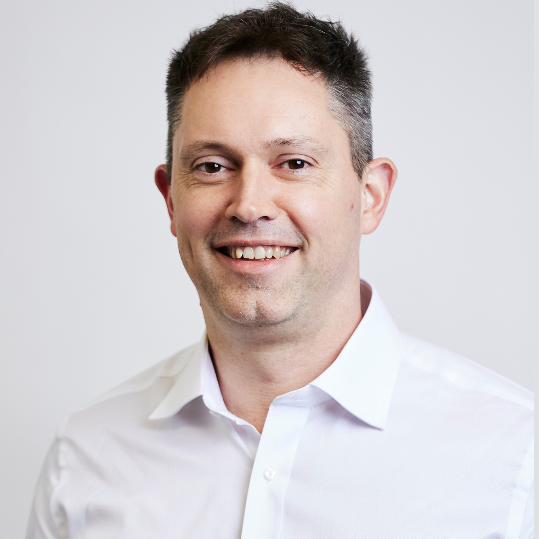 A man in a white shirt is smiling for the camera.