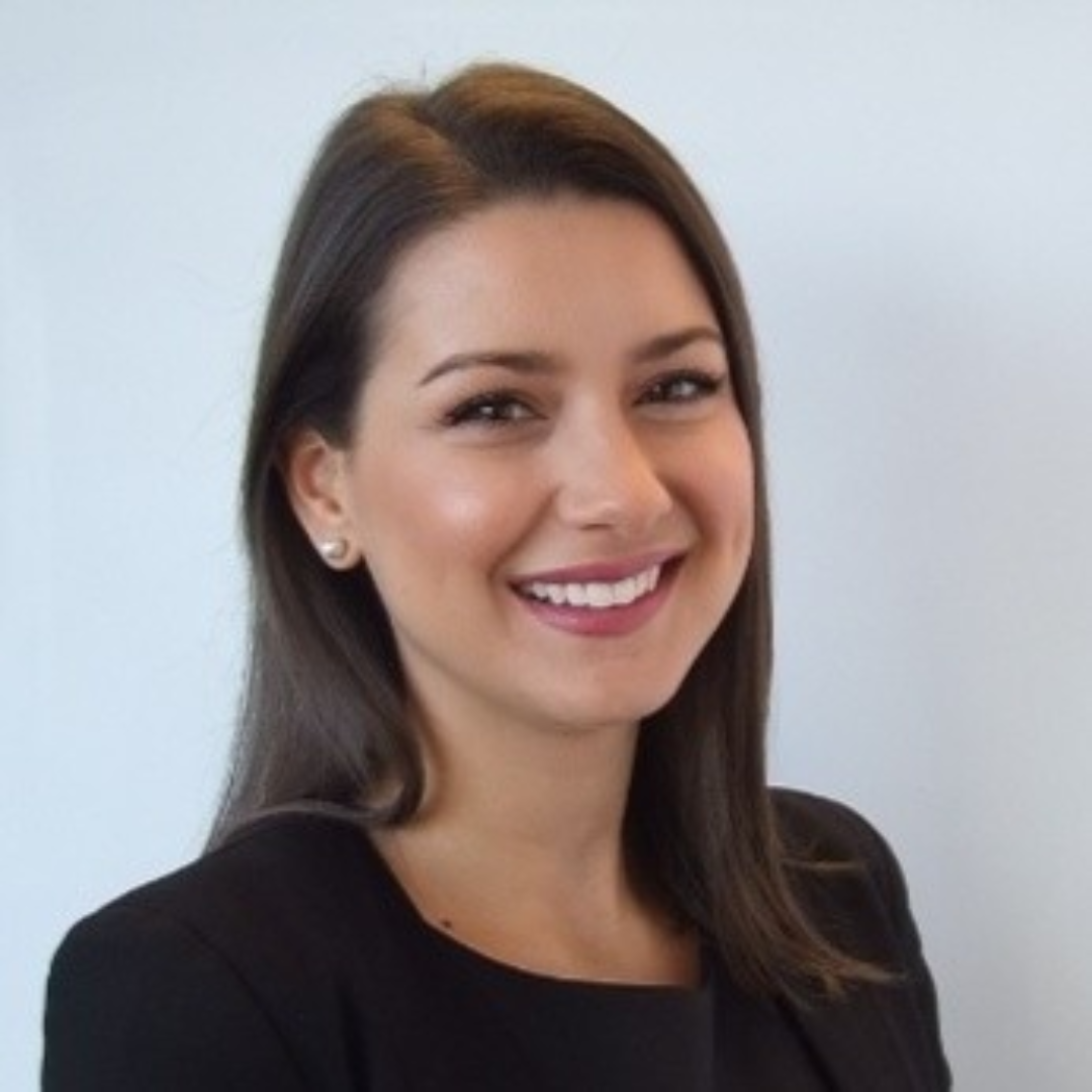A woman in a black jacket is smiling for the camera