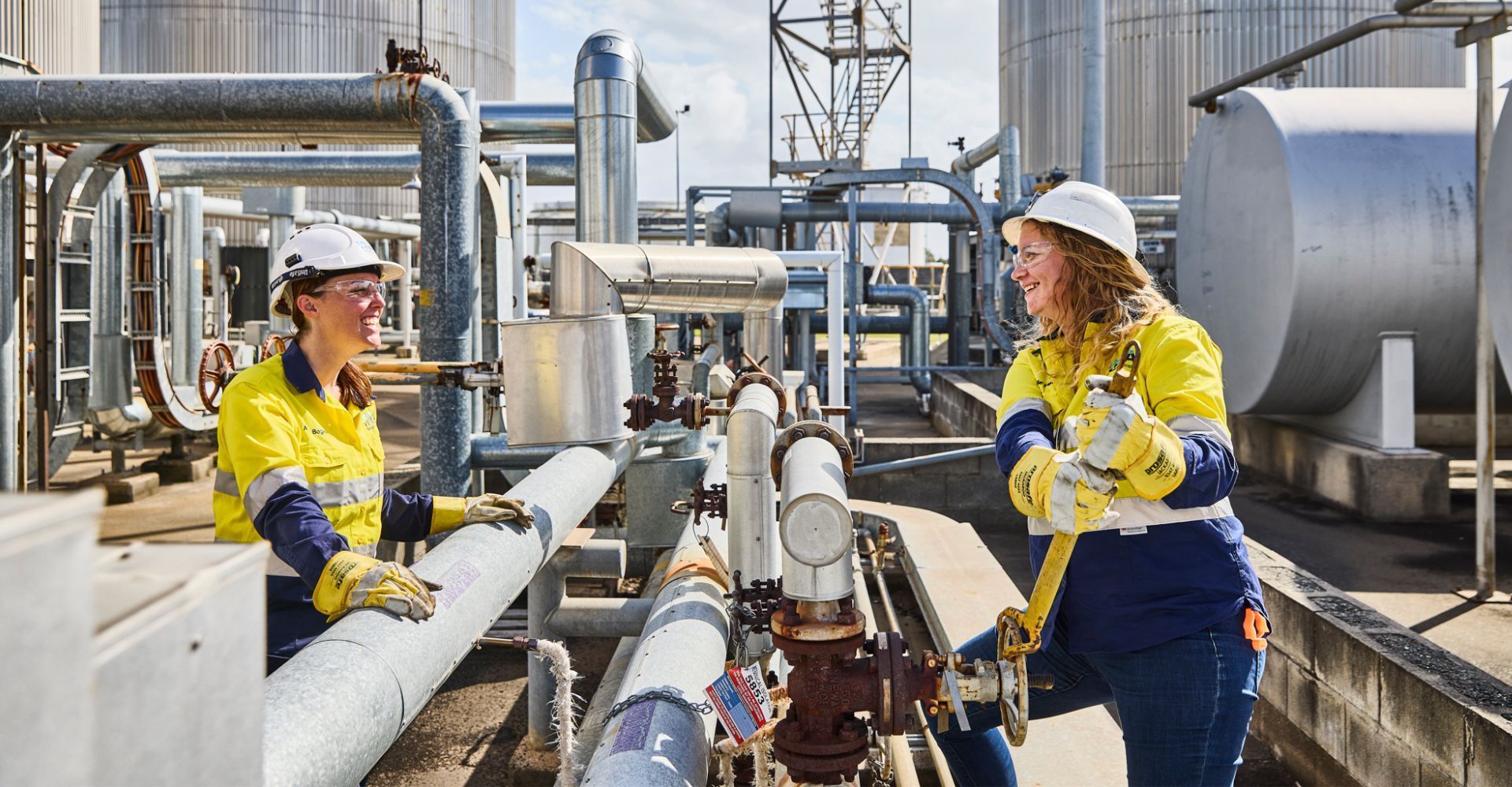 Two women are working on pipes in a factory.