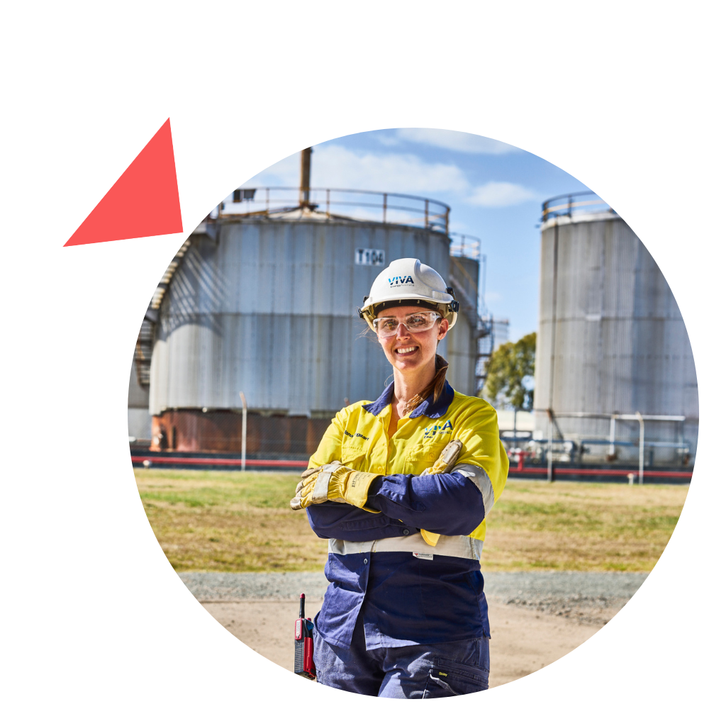 A woman in a hard hat is standing in front of a large tank.