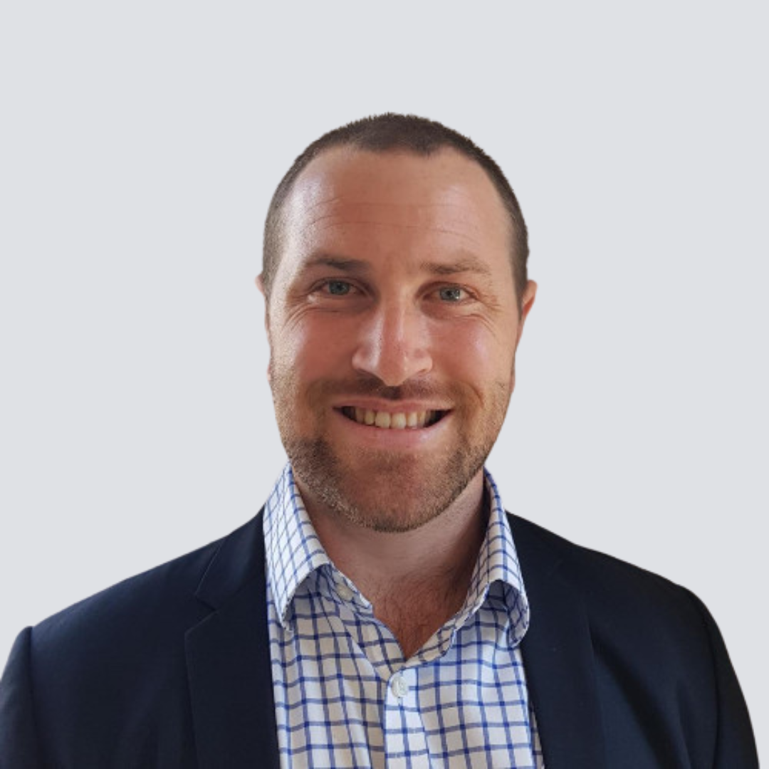 A man in a suit and plaid shirt is smiling for the camera.