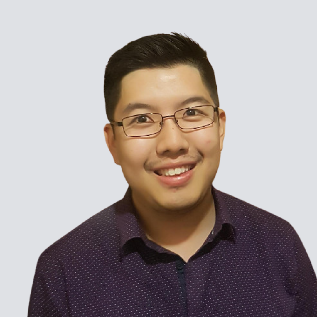 A man wearing glasses and a purple shirt smiles for the camera