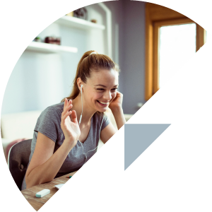 A woman wearing headphones is smiling while using a laptop computer