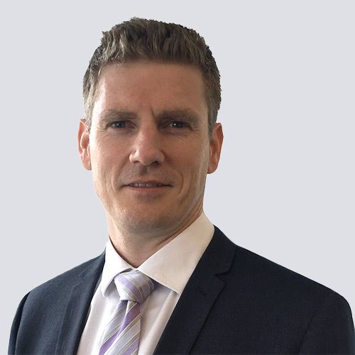 A man in a suit and tie is smiling for the camera.