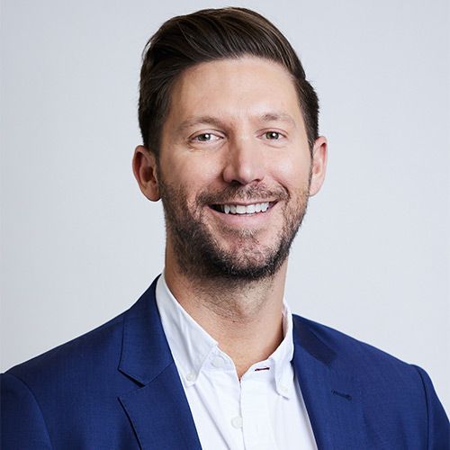 A man in a blue suit and white shirt is smiling for the camera.